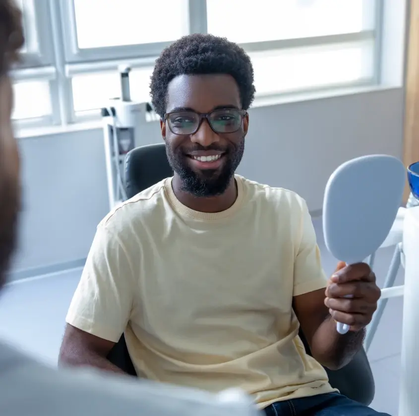 A happy patient admiring his smile in a hand mirror