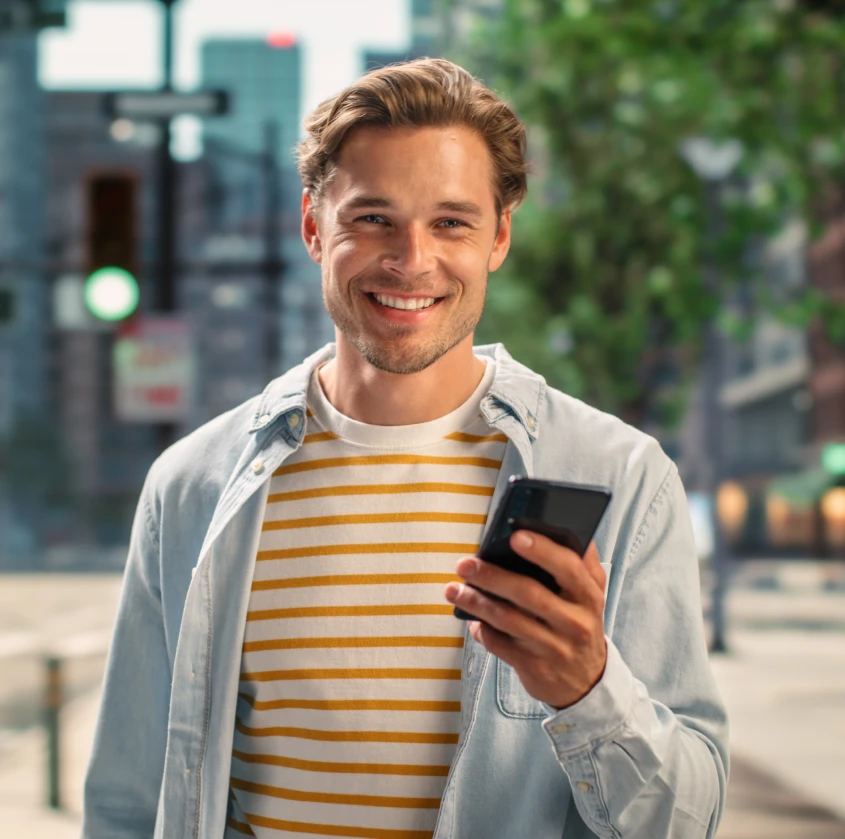 A smiling man checking his phone outdoors